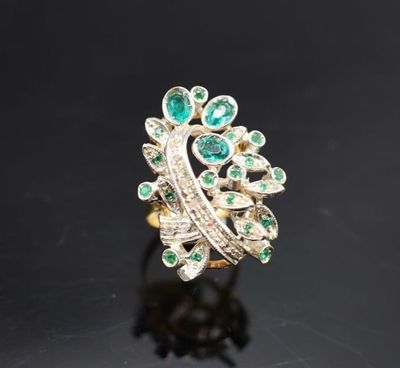Gros plan sur une bague en or ornée d'émeraudes et de diamants