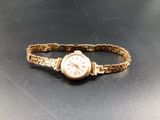 a gold bracelet with a watch on it on a table