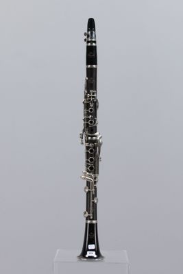 a close up of a clarinet on a stand with a gray background