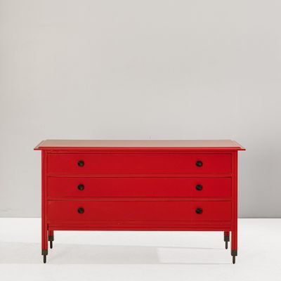 une commode rouge posée contre un mur blanc