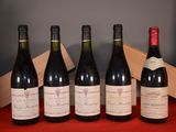 six bottles of wine are lined up on a red table