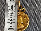 a picture of a gold plated pendant on a ruler