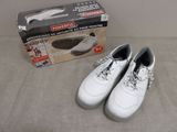 Il y a deux paires de chaussures blanches sur un lit, à côté d'une boîte à chaussures.