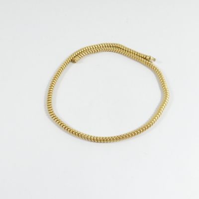 un bracelet plaqué or orné d'un motif en spirale sur fond blanc