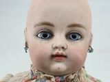 a baby doll with blue eyes sitting on a table