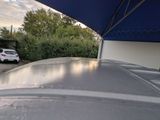 a car that is parked under an umbrella in the driveway