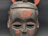 a close up of a wooden mask on a black background