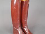 pair of brown leather boots with yellow soles on a gray surface