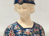 une figurine en céramique représentant une femme vêtue d'une robe bleue