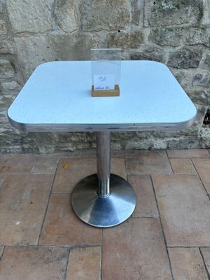 une table blanche sur laquelle est posée une carte, posée sur un sol en briques