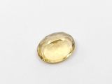 a yellow sapphire stone on a white surface