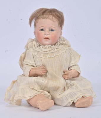 an antique doll sitting on a white surface wearing a white dress