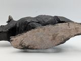 a sculpture of a cat laying on a piece of wood