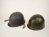 pair of wwii german steel helmets on a white background