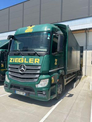 two green trucks parked next to each other in front of a building
