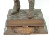 bronze statue of a man in a suit and boots on a base