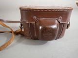 a brown leather camera case on a white table