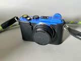 a black camera with a blue lens and a black strap