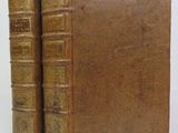 two old books sitting on top of each other on a white surface