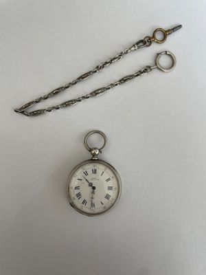 a silver pocket watch with a chain hanging from it ' s side