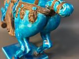 a blue statue of a man riding a horse on a blue base