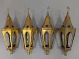 three gold colored lanterns hanging on a wall next to a white wall