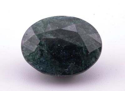 un gros plan d'un diamant vert et noir sur une surface blanche