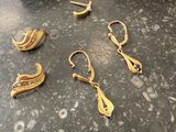 two pairs of gold earrings are sitting on a table next to a red box