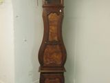 une grande horloge comtoise en bois, dans un coin de la pièce