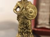 a gold figurine of a man holding a shield on a chess board