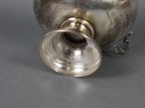 a silver vase with a metal lid on a table