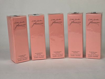 trois coffrets de parfum roses sont alignés sur une surface blanche