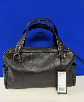 un sac à main noir muni d'une étiquette, posé sur une table