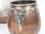 a small copper pot sitting next to a mirror