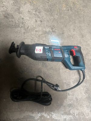 une perceuse filaire et un chargeur posés par terre