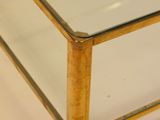 a glass coffee table with a gold frame on it