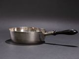 a silver saucepan with a black handle on a gray surface