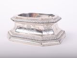 a silver ring on a stand on a white surface