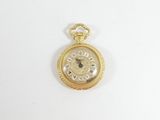 une image d'une montre de poche en or sur une surface blanche