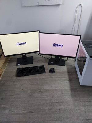 deux écrans d'ordinateur posés sur un bureau avec un clavier et une souris