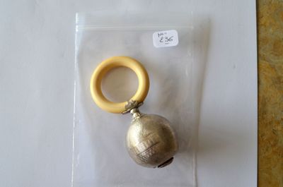 une clochette en argent et un anneau en bois dans un sac en plastique