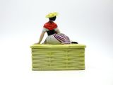 a figurine of a woman sitting in a basket