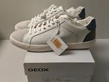 une paire de chaussures blanches et bleues posée sur une boîte blanche