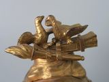 two birds sitting on top of a gold vase