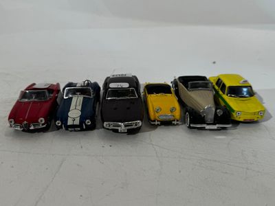 several toy cars are lined up in a row on a white surface