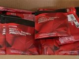des sachets rouges de protéines dans une boîte en carton posée sur une table