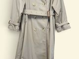trench coat hanging on a hanger on a white wall