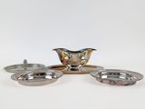 three silver plated dishes and a saucer on a white surface