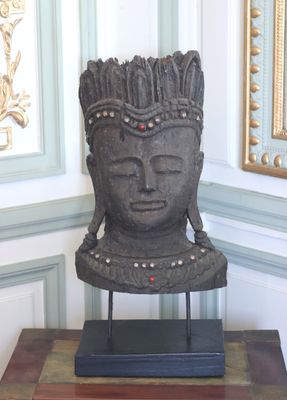 une statue représentant une tête posée sur une table devant un mur