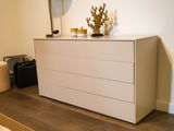 a white dresser in the corner of a room with a lamp on it